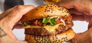 La Fiore de Firehouse – hamburguesa con queso, lechuga y tomate sostenida por dos manos