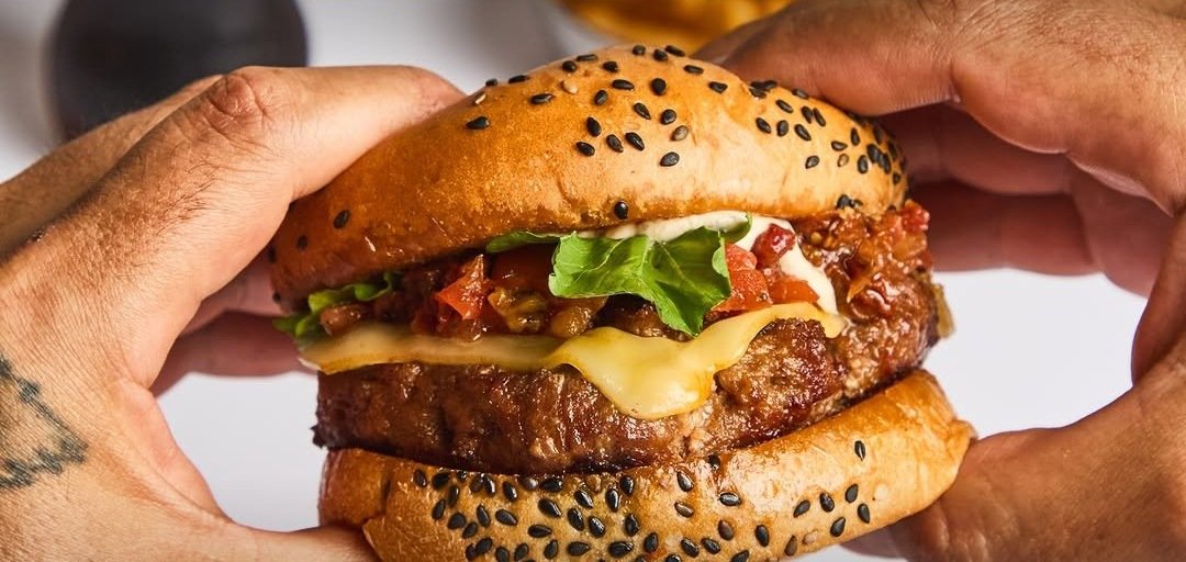 La Fiore de Firehouse – hamburguesa con queso, lechuga y tomate sostenida por dos manos